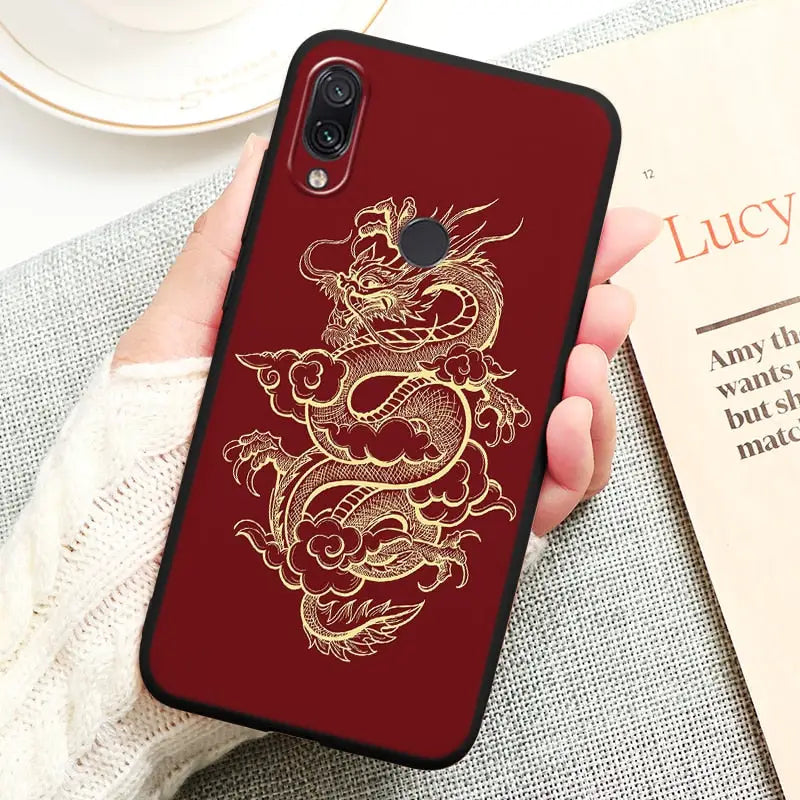a woman holding a red phone case with a gold dragon on it