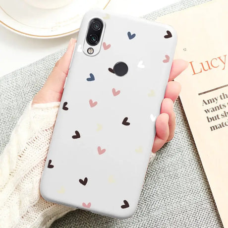 a woman holding a phone case with hearts on it