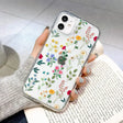 a woman holding a phone case with flowers on it