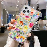 a woman holding up a phone case with colorful flowers on it
