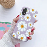 a woman holding a phone case with white flowers on it