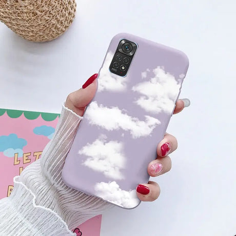 a woman holding a phone case with clouds on it