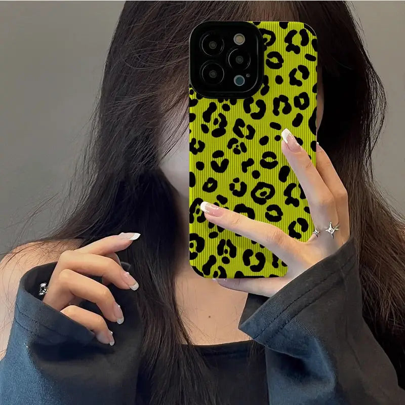 a woman holding up her phone case with a yellow leopard print