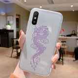 a woman holding up a phone case with a purple dragon on it