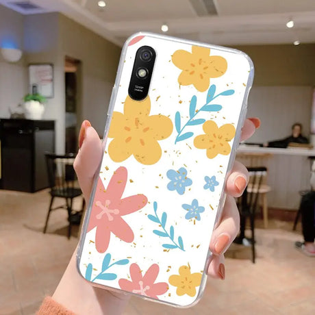 a woman holding up a phone case with flowers on it