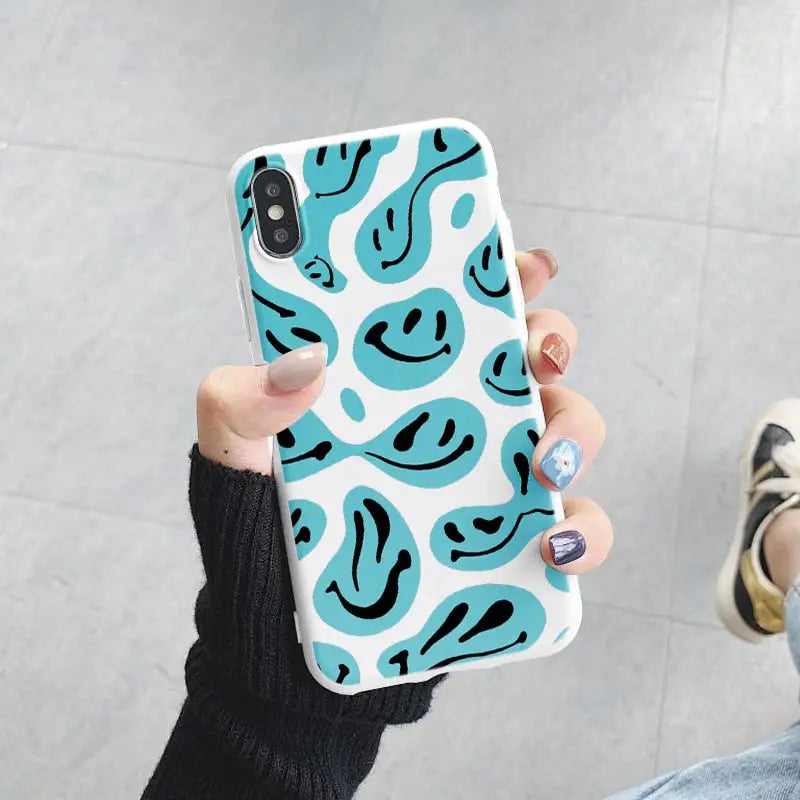 a woman holding up a phone case with a blue and white pattern