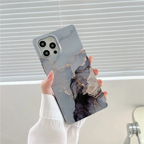 a woman holding up a phone case with a marble pattern