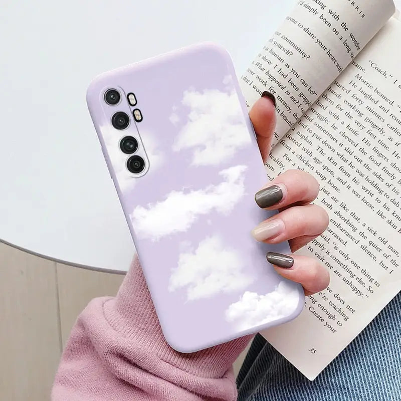 a woman holding a phone case with clouds in the sky