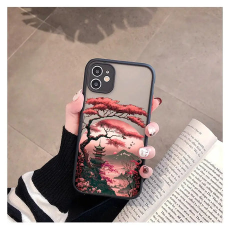 a woman holding a phone case with a pink tree on it