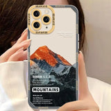 a woman holding up a phone case with mountains in the background