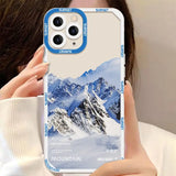 a woman holding up a phone case with a mountain print