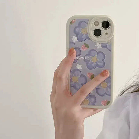 a woman holding a phone case with flowers on it