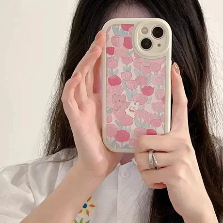 a woman holding a phone case with flowers on it