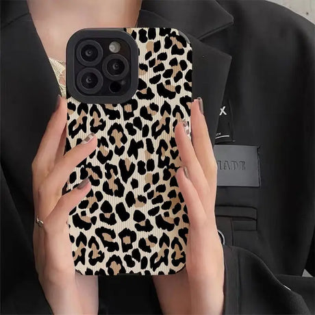 a woman holding a phone case with a leopard print