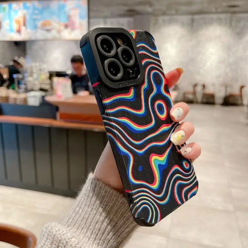 a woman holding up a phone case with a rainbow swirl design