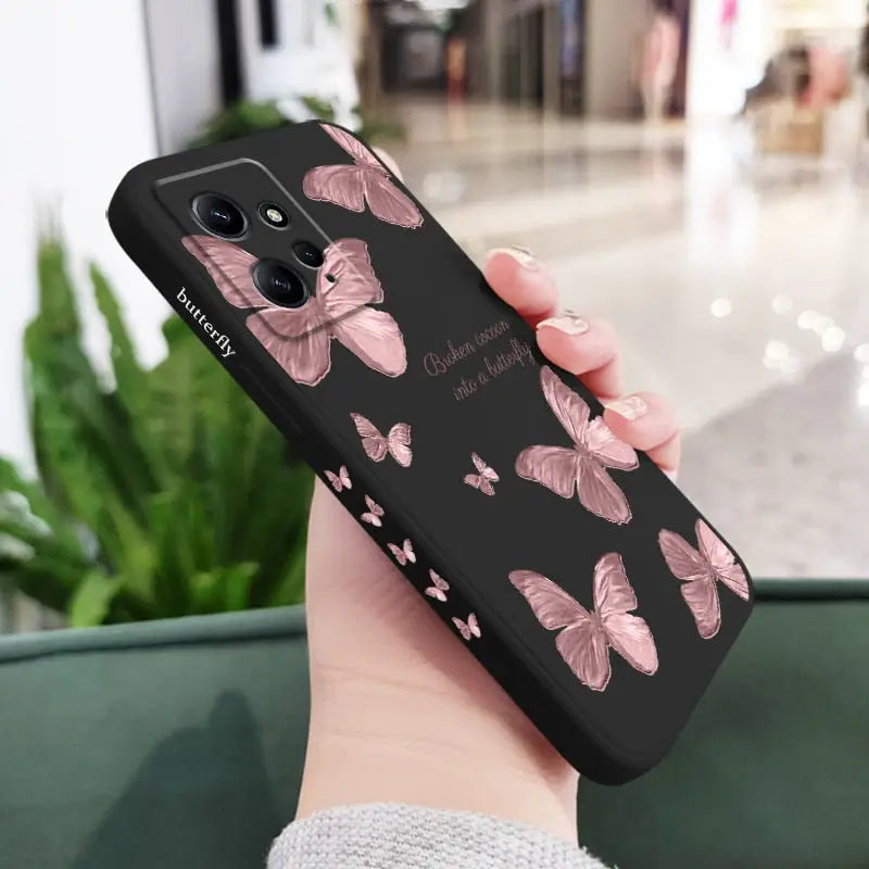 a woman holding a phone case with pink butterflies on it