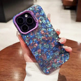 a woman holding a phone case with blue and pink shards