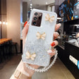 a woman holding up a phone case with glitter butterflies