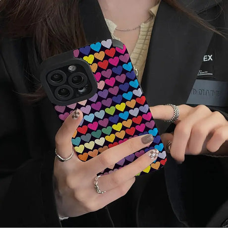 a woman holding a phone case with hearts on it