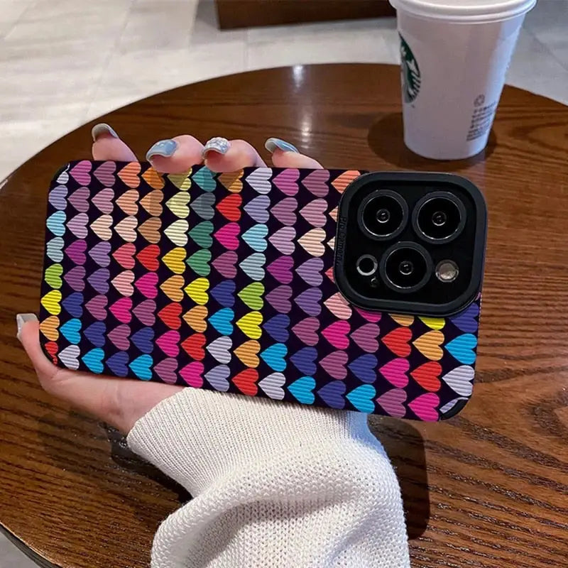 a woman holding a phone case with colorful hearts on it