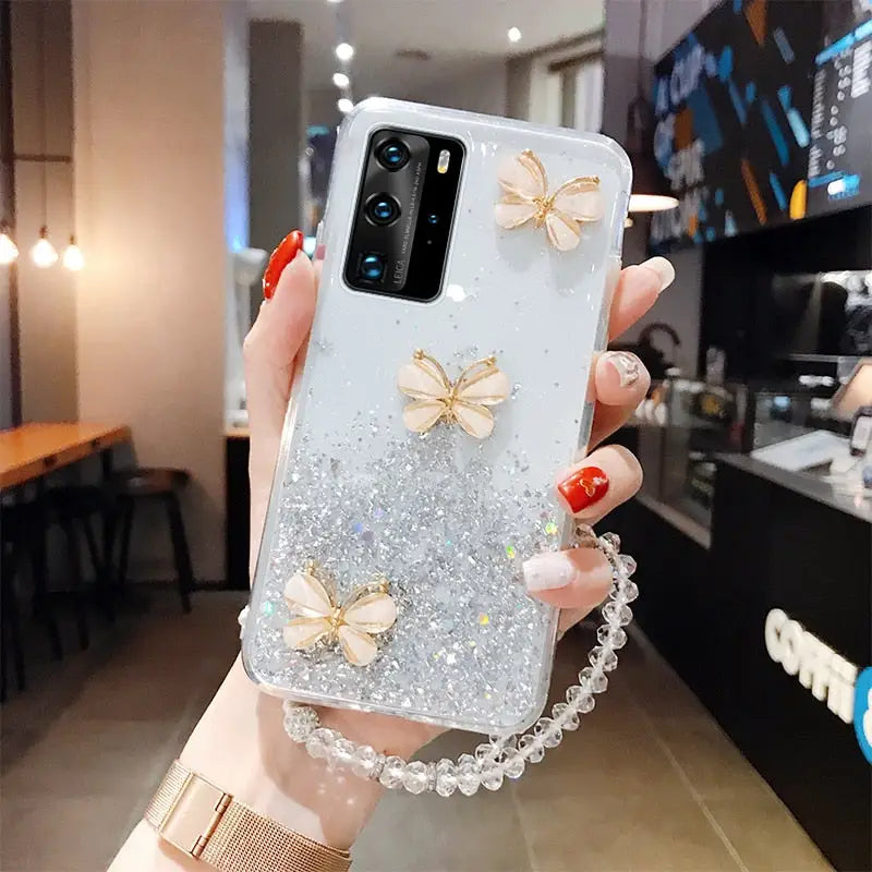 a woman holding a phone case with glitter butterflies on it