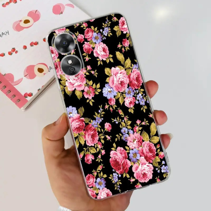 a woman holding a phone case with pink flowers on it