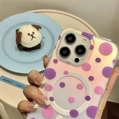 a woman holding a phone case with a pink and purple polka dot pattern