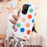 a woman holding a phone case with colorful polka dots