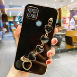 a woman holding up a phone case with heart charms