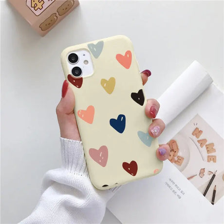 a woman holding a phone case with hearts on it