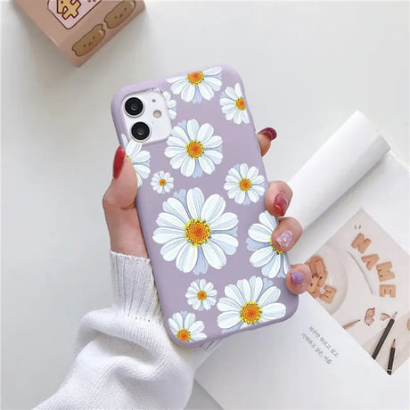 a woman holding a phone case with white flowers on it