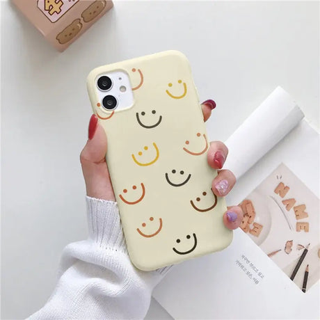 a woman holding a phone case with a smiley face on it