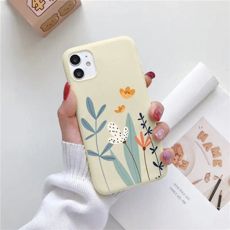 a woman holding a phone case with flowers on it