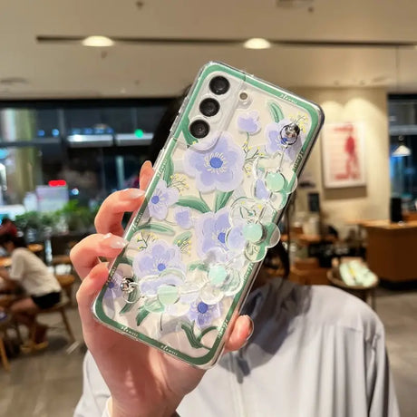 a woman holding up a phone case with flowers on it