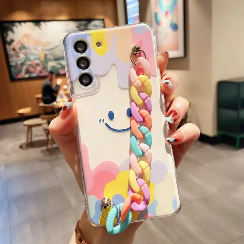 a woman holding up a phone case with colorful hearts