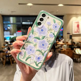 a woman holding up a phone case with flowers on it