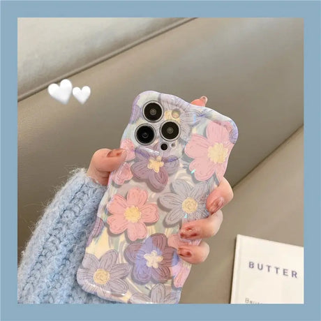 a woman holding a phone case with flowers on it