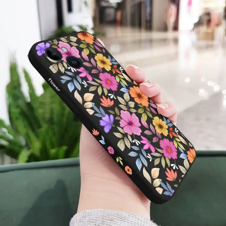 a woman holding a phone case with flowers on it