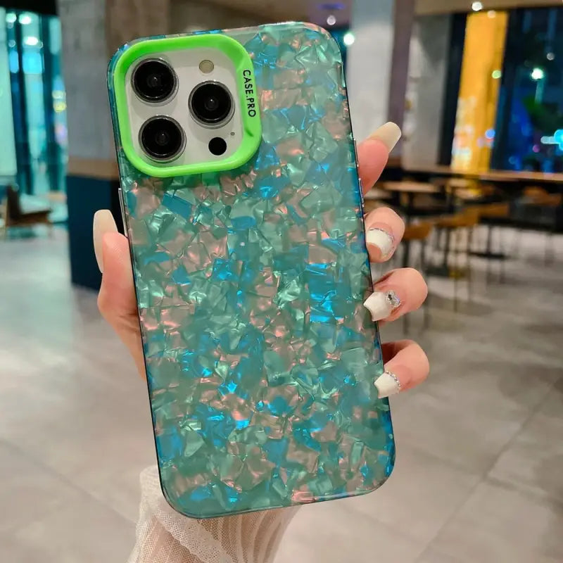 a woman holding a phone case with a green and blue marble pattern