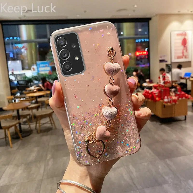 a woman holding up a phone case with a pink glitter phone cover
