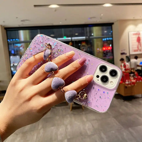 a woman holding a phone case with glitter on it