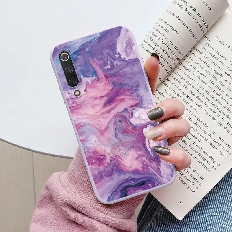 a woman holding a phone case with purple marble