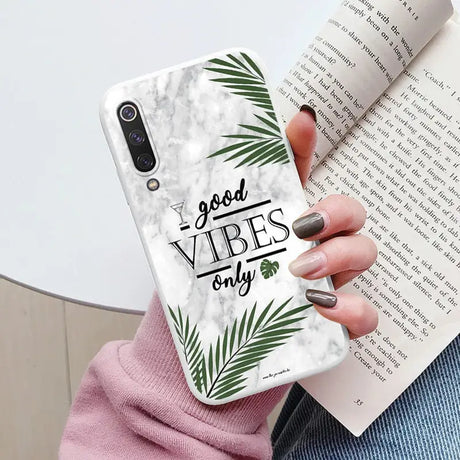 a woman holding a phone case with the words good vibes on it