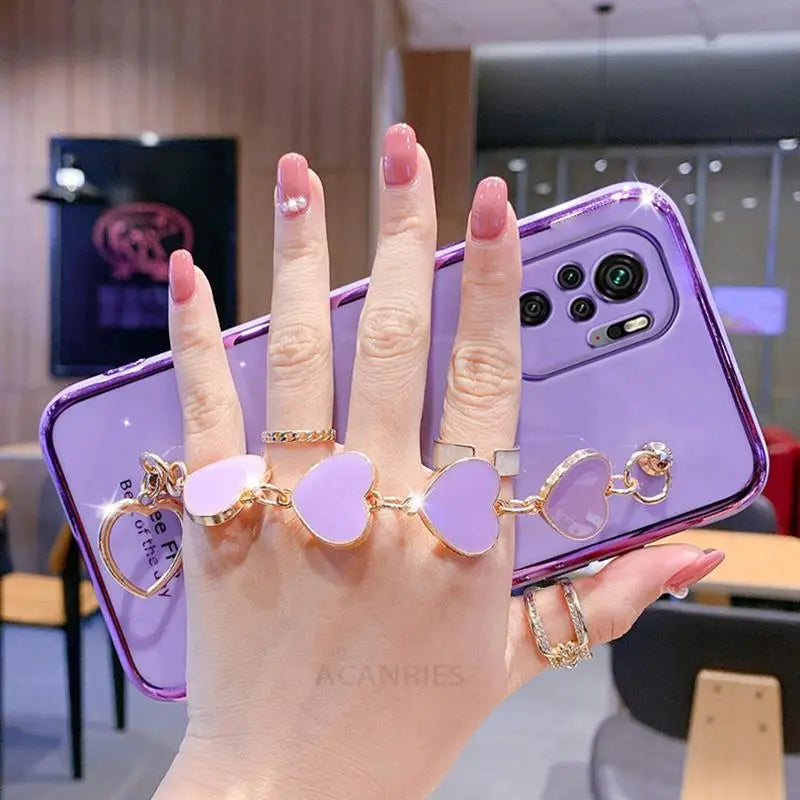a woman holding up her phone case with two heart shaped rings