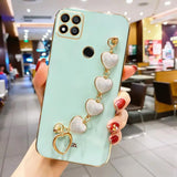 a woman holding a phone case with heart charms