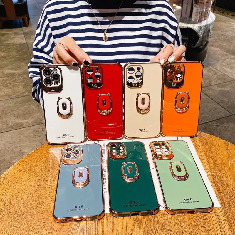 a woman holding a phone case with multiple colors