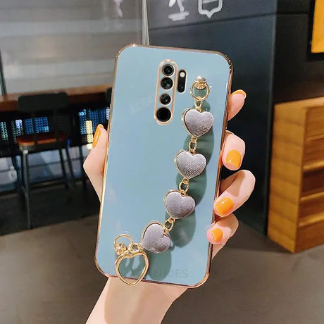 a woman holding a phone case with a heart charm