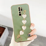 a woman holding a phone case with heart charms
