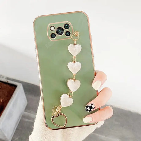 a woman holding a phone case with heart charms