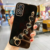 a woman holding up a phone case with heart charms